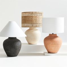 three different colored vases sitting next to each other with lamps on top of them