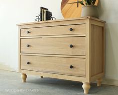 a wooden dresser sitting next to a wall with a clock on it's side