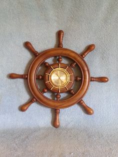 a wooden steering wheel with brass spokes on a light blue blanketed surface in the shape of a ship's helm