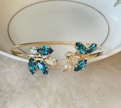 Pretty open bangle bracelet featuring 8x4mm and 10x5mm Swarovski crystals in shades of champagne and teal. Bracelet is adjustable, opens from the top. Thanks for stopping by!