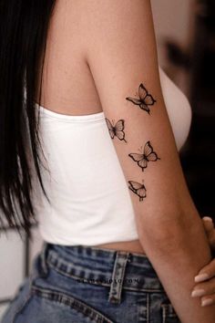 a woman's arm with three butterflies tattooed on the left side of her arm