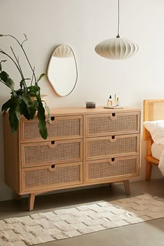 a bedroom with a bed, dresser and mirror on the wall next to plants in vases