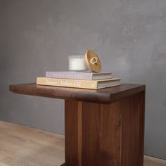 a stack of books sitting on top of a wooden table next to a white candle