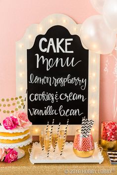 a table topped with cake and desserts next to a chalkboard sign that reads cake menu lemon raspberry cookies cream vanilla bean