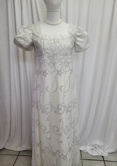 We offer a Regency styled gown, with the empire waist and short puffed sleeves.  Perfect for a themed wedding or Regency event.  This stunning dress has a silver embroidered lace overlay and is fully lined.  The neckline has been trimmed with white lace trim.       *This gown ties at the back with ribbons which can adjust the fit.      * All seams have been finished and this gown is spot clean or dry clean only.   If you have any questions about this dress, or any of our listings, please convo u Bridgerton Daphne, Historic Dresses, Jane Austen Emma, Bridgerton Dresses, Shifting Board, Regency Dresses, Regency Dress, Oc Outfits, Dr Wardrobe