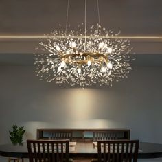 a chandelier hanging from the ceiling above a dining room table with chairs around it