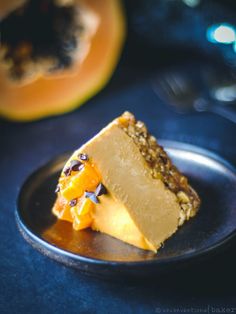 a piece of cake sitting on top of a black plate next to an orange slice