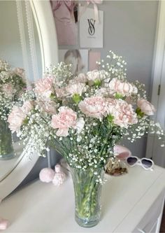 pink carnations and baby's breath in a vase on a white dresser