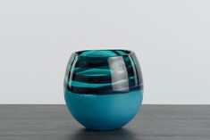 a blue and black vase sitting on top of a wooden table next to a white wall