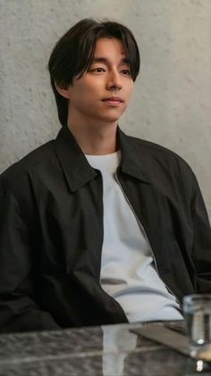 a young man sitting at a table with a glass of water in front of him