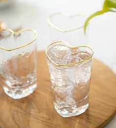 two heart shaped glasses sitting on top of a wooden tray