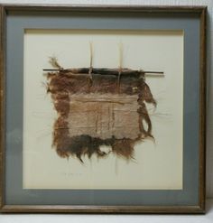 an old piece of cloth hanging in a frame on the wall next to a white wall