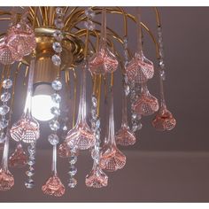 a chandelier hanging from the ceiling with pink glass beads and crystal drops on it