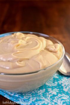 a bowl filled with cream sitting on top of a blue and white napkin next to a spoon