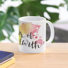 a white coffee mug with the words days of earth printed on it next to a book