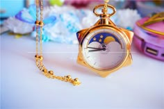 a gold pocket watch sitting on top of a table next to a chain link necklace