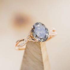 an engagement ring with a large blue stone surrounded by small white diamonds on top of a wooden stand