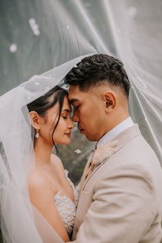 a bride and groom standing under a veil