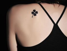 a woman with a four leaf clover tattoo on her back