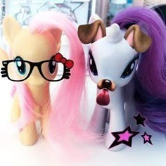 two little pony dolls are next to each other on a table with pink and purple hair