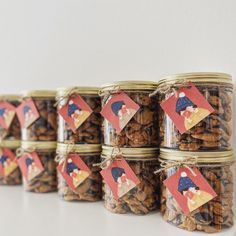 several jars filled with nuts on top of a white table next to a red and blue tag