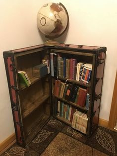 an old bookcase with a globe on top and books in the bottom, sitting next to a wall