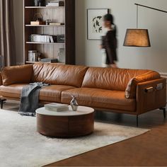 a living room with a brown leather couch and coffee table in front of a book shelf