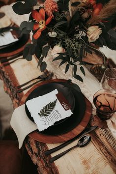 the table is set with black plates and place settings