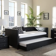 a black daybed sitting in a bedroom next to a dresser with drawers on each side