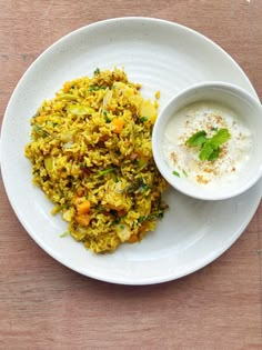 a white plate topped with rice and veggies next to a bowl of yogurt