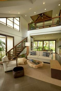 a living room filled with lots of furniture and a stair case in front of it