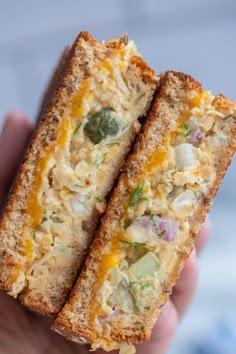 two pieces of bread with cheese and vegetables on them are held in the palm of someone's hand