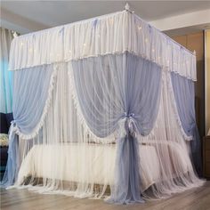 a canopy bed with sheer drapes and lights on the top, in a living room