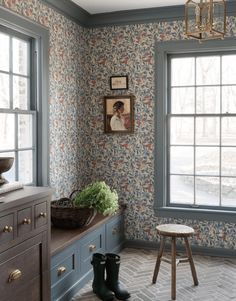 a room with blue walls and floral wallpaper on the walls, along with a wooden bench in front of two windows