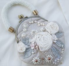 Bohemian purse bag hand embroidered! Unique Evening bag! A unique bag with an ingenious mix of materials! Beautiful bag for the bride. A bag in romantic vintage look for you, your daughter or granddaughter.  An exceptional accesoire for an unforgettable day.  Beautiful selected textile combination of different materials and in different shades of whites embroidered. I left my unbridled imagination sewing and embroidery a free rein here. Exquisite Italian embroidered with silver linen with Italian fabric roses, natural pearls and glass beads only  A filigran embroidery in shades of white highlight on a silver lines around the white flowers and fine details. This fanstatic work, I can not repeat. Its really absolute unique. width 7,4 inc (19cm) height 8 inc (20cm) frame width 5 inc (13cm) ba Embroidery Purse, Bohemian Purse, Vintage Evening Bags, Embroidered Handbag, Bohemian Bags, Floral Purse, Wedding Unique, Sewing And Embroidery, Crochet Rope