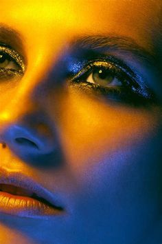 a woman's face with bright blue and yellow lights on her eyes, close up