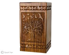 a wooden box with an intricate carving on the front and sides, depicting birds flying around a tree