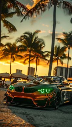 an orange and green sports car parked in front of palm trees on the beach at sunset