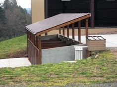 a building with stairs leading up to the top and below it, in front of a grassy hill