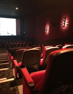 an empty theater with red seats and projector lights on the wall behind them,