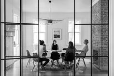 four people sitting at a table in front of large glass windows looking into the living room