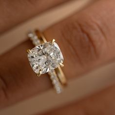 a woman's hand with a diamond ring on top of her finger and an engagement ring in the middle