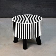 a black and white striped stool sitting on top of a cement floor