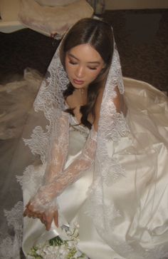 a woman in a wedding dress cutting into a cake