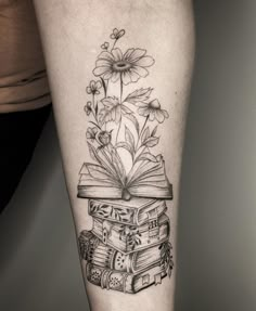 a woman's leg with books and daisies on it, as if she were reading