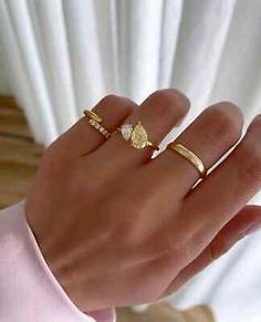 a woman's hand with two gold rings on top of her finger and the other ring