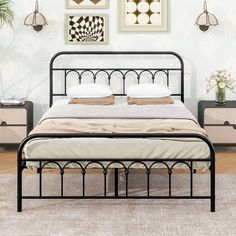 a black metal bed frame with two pillows on it and pictures above the headboard