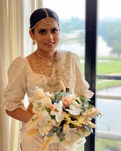 a woman in a white dress holding a bouquet of flowers and wearing pearls on her head