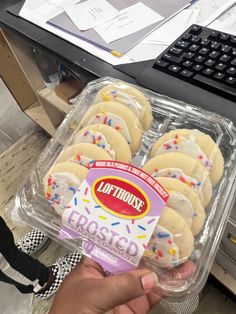 a person holding a box of cookies in front of a keyboard