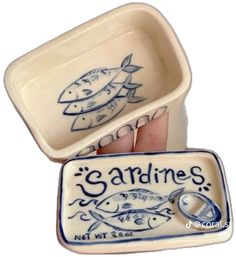 someone is holding two ceramic dishes with fish designs on the bottom and one has a ring in it